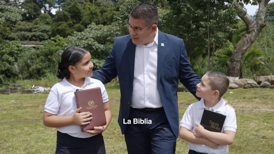 Fabricio Alvarado caminando con dos niños mientras sostienen la biblia